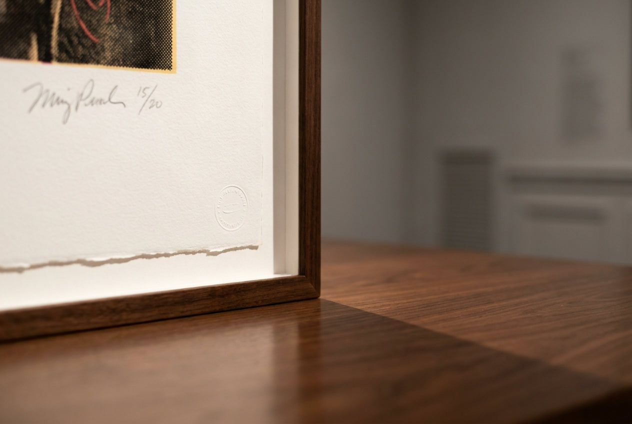 Close-up of the signed and numbered lower edge of a framed pop-art print on a gallery table
