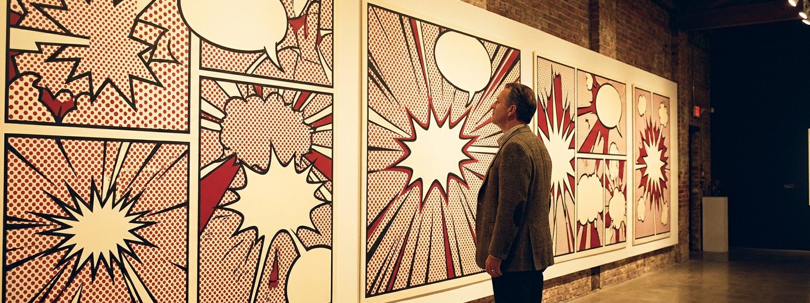 A gallery wall of original pop-art comic-style abstract prints under warm champagne-gold light