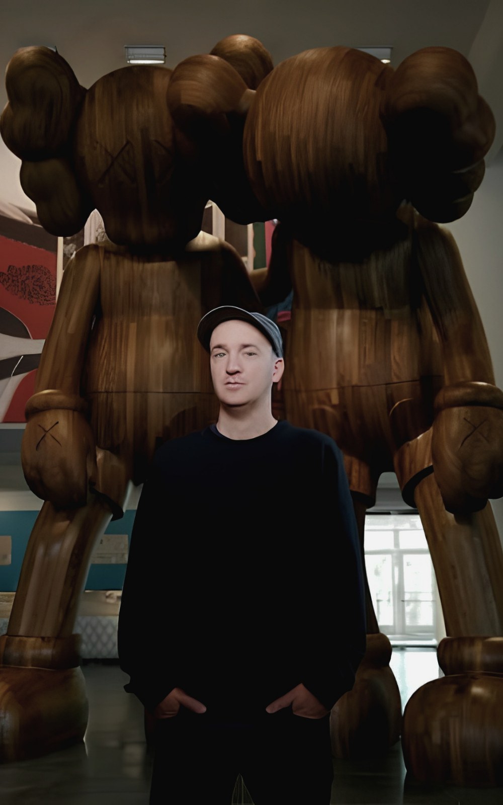 The artist KAWS (Brian Donnelly) standing before a monumental wooden Companion sculpture